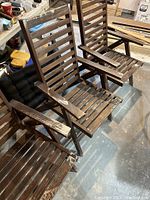 Three dark stained wood folding patio chairs with slatted design and armrests; wood shows wear and finish fading.