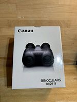 Front of retail box showing Canon branding and model “Binoculars 8×20 IS”