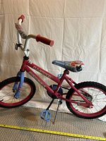 Photo of pink kids bicycle showing side view including handlebars, pedals, tires, and kickstand.