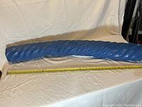 Full length side view of large blue pool noodle showing textured surface and length measurement