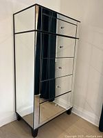 Front and side view of the tall mirrored dresser showing five drawers and black framing