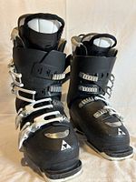 Front view of the pair of Fischer women's ski boots showing black plastic shell with four silver buckles and white padded liner.