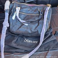 Full front view of the black distressed leather purse with dual handles and adjustable shoulder strap, set on a Botkier dust bag.