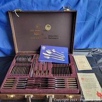 Open fitted box showing full service for 12 in two layers, certificates to right