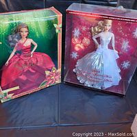 Two boxed Holiday Barbie dolls side-by-side, one from 2008 in white and silver gown, and one from 2022 in red dress.