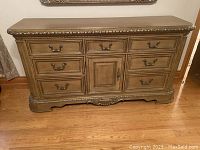 Full frontal view of wooden dresser showing six drawers and one central cabinet door with metal handles