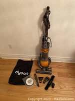 Full view of upright vacuum and laid out attachments on floor