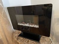 Electric fireplace powered off showing clear crystal decoration inside the black glass frame.