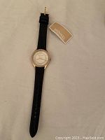 Full view of Michael Kors wristwatch with black leather strap and attached tag.