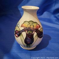 Front and side views of the vase showing colorful floral design on cream ceramic body.