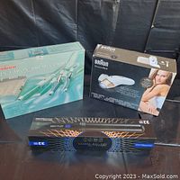 Photo shows three boxed personal care items including Sunbeam 4-in-1 Iron/Brush Combo, Braun Silk-épil Pro 5 Epilator, and 32-piece haircutting kit.