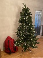 Full view of assembled 7.5-ft artificial tree with integrated lights and red storage bag at base