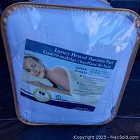 Front view of the new luxury heated mattress pad in packaging showing label with product details and image of woman resting.