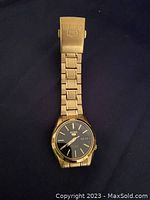 Full view of the gold tone Seiko 5 ladies watch with black dial and fold over clasp spread out.