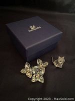 Two Swarovski crystal figurines (star cluster and cat) and blue Swarovski box on black background.