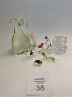 Topview of whole set showing six different glass animal figurines and one decorative piece arranged on white background.
