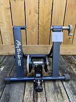 Front view showing black metal frame, resistance unit center, adjustable clamp on right side, and Masterfab branding on left side bar.