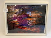 Full front view of framed abstract art with shades of purple, orange, red and black.