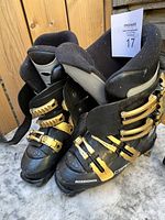 Pair of black and gold Rossignol ski boots, showing front and side views with adjustable buckles and padded inner lining.