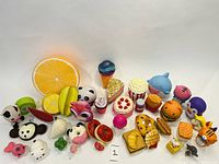 Overview photo showing entire squishy toy collection including food items, animals, and large orange slice toy.