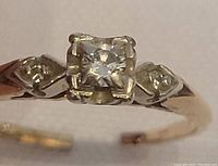 Close-up of ring head showing round-cut center diamond and decorative shoulder accents