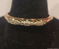 Front view of vintage gold ring showing alternating gold tone decorative circular and curved shapes on top.