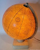 Illuminated 12 inch globe showing North Atlantic and surrounding regions mounted on white wooden square base with metal meridian holder.