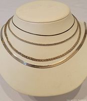 Four sterling silver chains displayed on necklace stand showing varying chain styles and thicknesses