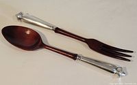 Photo showing the full pair of salad servers: one fork and one spoon, with dark wooden handles and silver ends.