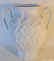 Front view of white ceramic vase with stylized raised leaf pattern and dual handles.