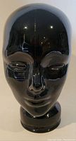 Front view of the black glass head mannequin showing facial features and shiny surface.