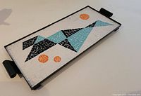 Tray angled view showing full design and handles, highlighting geometric tiled pattern in black, turquoise, and orange on white.