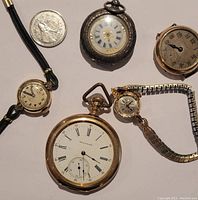 Group photo of five vintage watches with a quarter for scale; shows all items