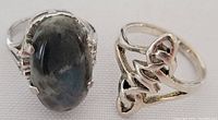 Photo showing both rings side by side on white background; one ring with dark marbled stone, the other with open silver design.