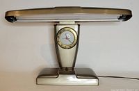 Front view of the vintage airplane style lamp showing the wide horizontal light and clock on trapezoidal base.