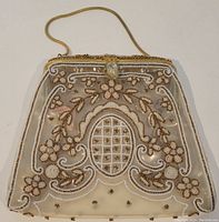 Full view of vintage French clear plastic purse decorated with gold and white bead floral patterns and gold metal chain handle.
