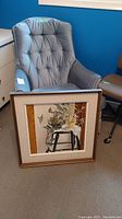 Full front view of framed painting leaning against a chair, showing subject and frame.