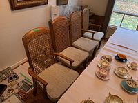 Overview of four chairs (two side chairs and two captain’s chairs) positioned next to dining table showing style and finish.