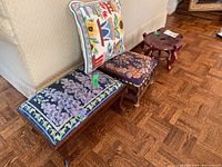 Full view of the two embroidered foot stools and small cushion against the couch