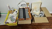 Wide view showing all knitting needles, yarn skeins, needlepoint canvases, kits and crafting accessories arranged on floor