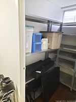 Side view of shelving units showing contents that are not included, with plastic storage bins on shelves and parts on floor.