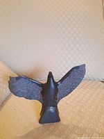 Front view of the soap stone bird figurine depicting its carved details on wings and body in a dark stone material.