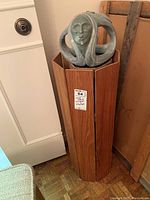 Full view of soapstone sculpture mounted atop octagonal wooden stand