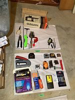 Overview of the lot including hand tools, measuring tapes, natural gas detector, pipe cutter, and other items arranged on white cloth on the ground.