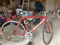 Full side view of red Trek Alpha SL 2100 bicycle showing frame, wheels, saddle, helmet on top tube