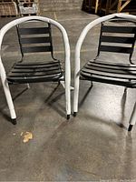 Two black metal chairs with white foam protection on frames shown side by side on concrete floor.