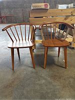 Two solid wood accent chairs side by side, showing front view with curved backs and spindle design.