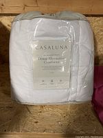 Front view of packaged Casaluna Down Alternative Comforter showing brand and key features.