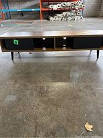 Front view of console table showing full length and compartments with black sliding doors and open middle section.