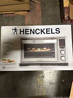 Photo of the box front showing Henckels convection countertop oven with digital controls and a pizza inside the oven.